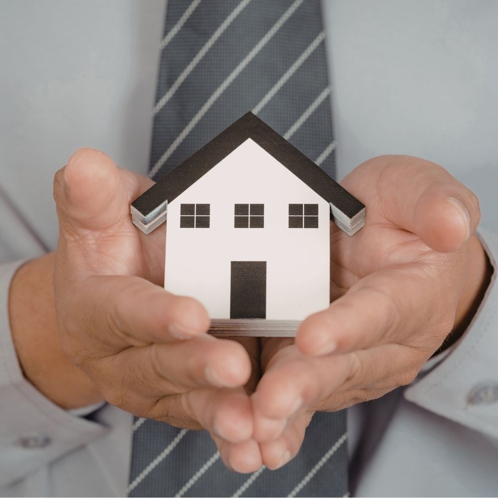Hands holding a model house, illustrating what does a management agent do for landlords and property owners